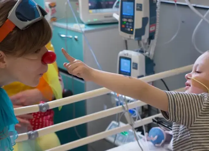 Child holding hands with a Clowndoctor in a hospital setting