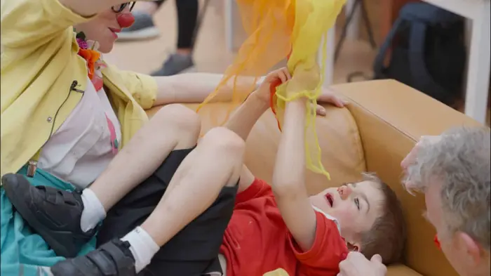 Clowndoctors connecting with young patient in hospital bed