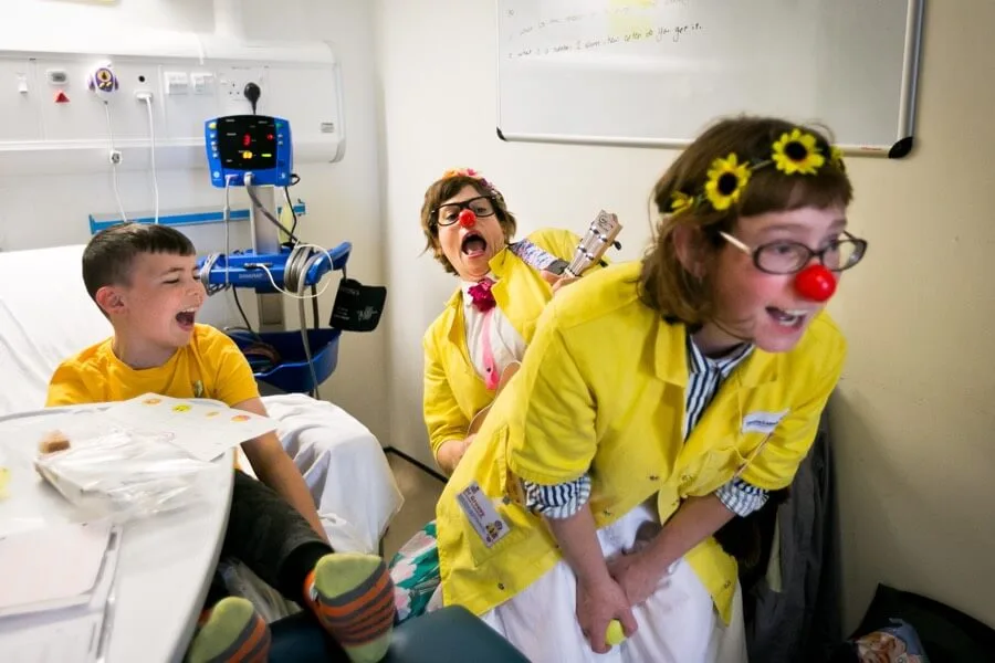 A Clowndoctor smiling and connecting playfully with a child at hospital bedside