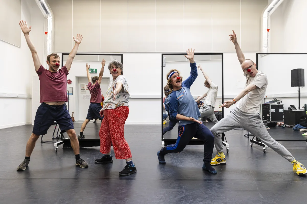 Performers with arms up during physical clown exercise