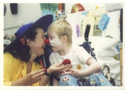 A child in hospital touches their nose against a Clowndoctors nose
