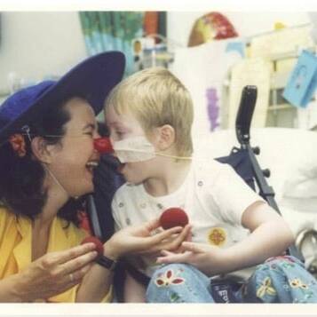 A child in hospital touches their nose against a Clowndoctors nose
