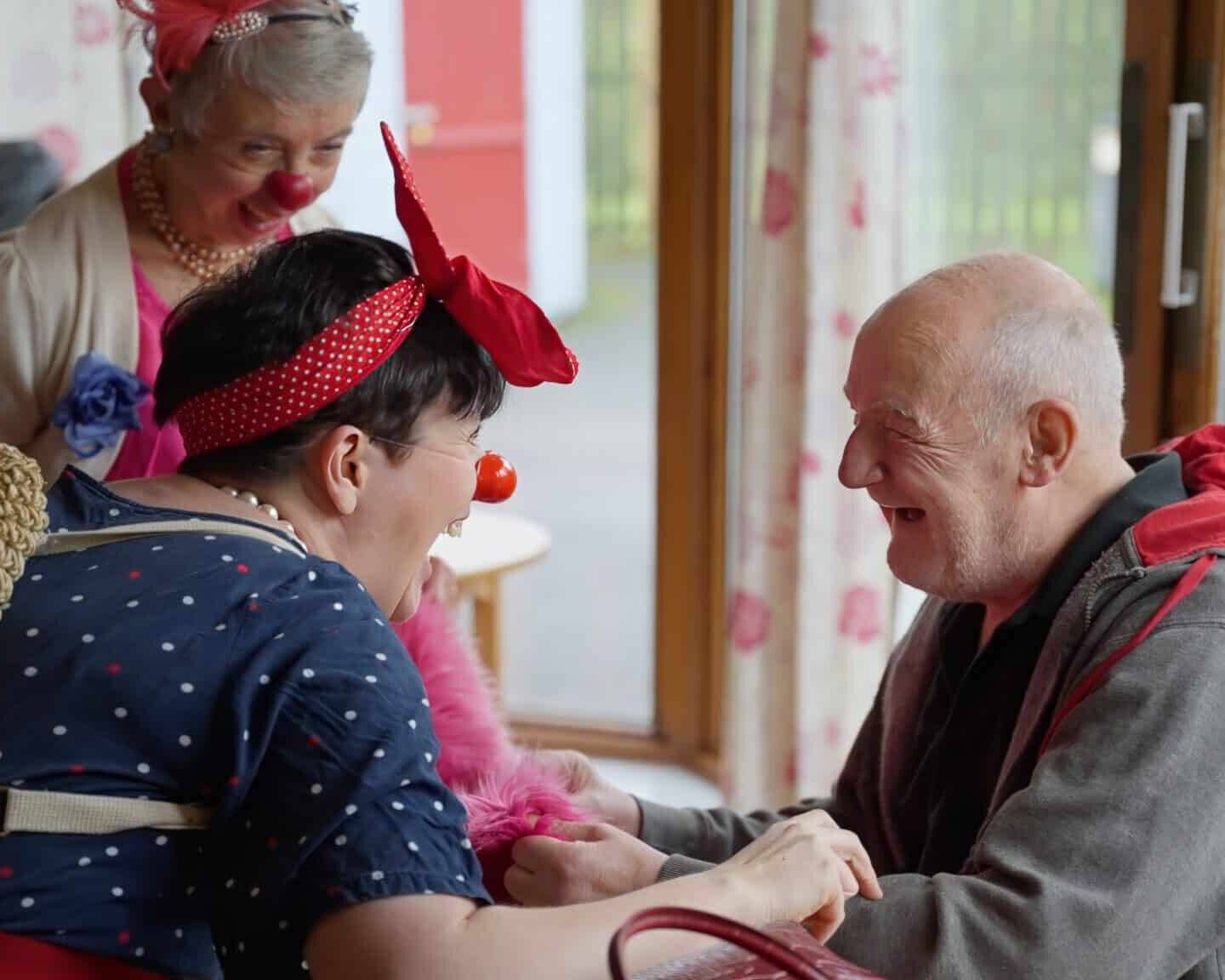 Dotty and Dipsy Elderflower visit a gentleman. Dotty is walking her fingers over his arm and he is laughing.